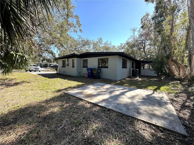 rear view of house featuring cooling unit, a yard, and concrete block siding