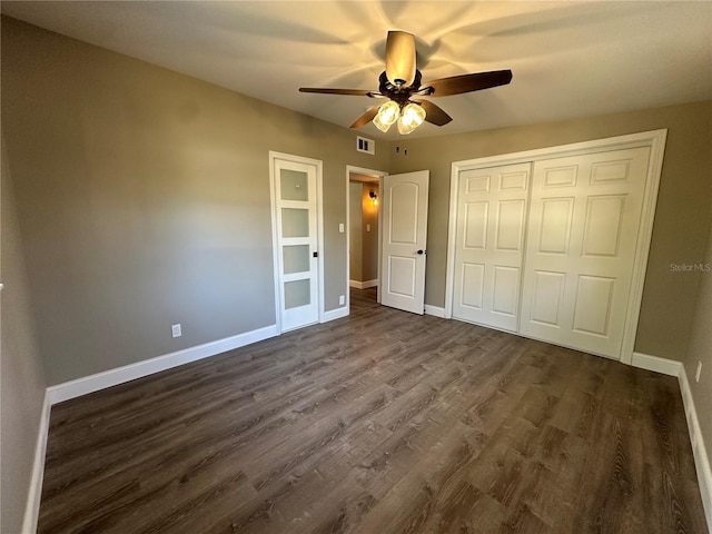 unfurnished bedroom featuring baseboards, a closet, dark wood-style floors, and a ceiling fan
