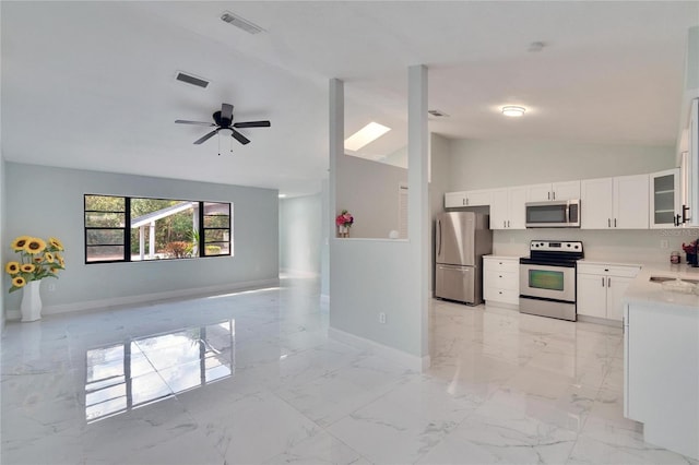 kitchen with sink, high vaulted ceiling, appliances with stainless steel finishes, ceiling fan, and white cabinets