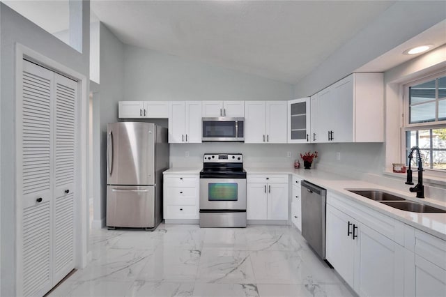 kitchen featuring lofted ceiling, sink, white cabinets, and appliances with stainless steel finishes