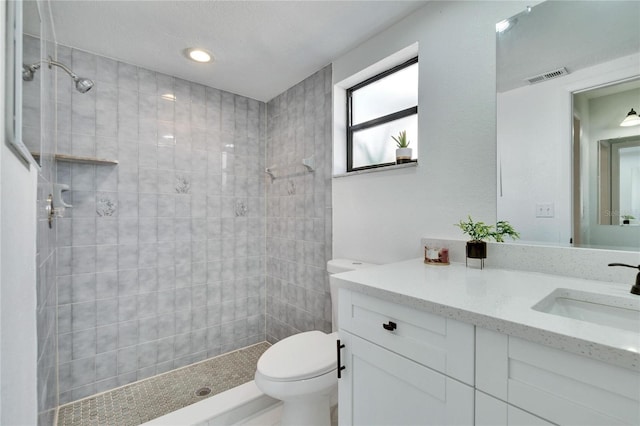 bathroom featuring vanity, toilet, and a tile shower