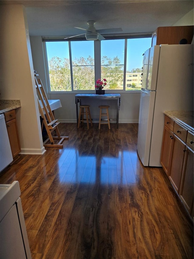 kitchen featuring ceiling fan, plenty of natural light, dark wood-type flooring, and white appliances