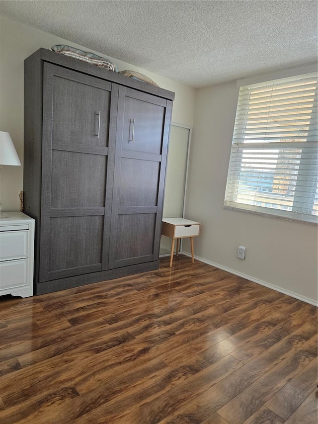 unfurnished bedroom with dark hardwood / wood-style floors and a textured ceiling