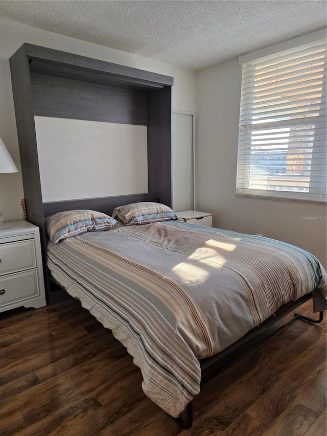 bedroom with dark hardwood / wood-style floors and a textured ceiling