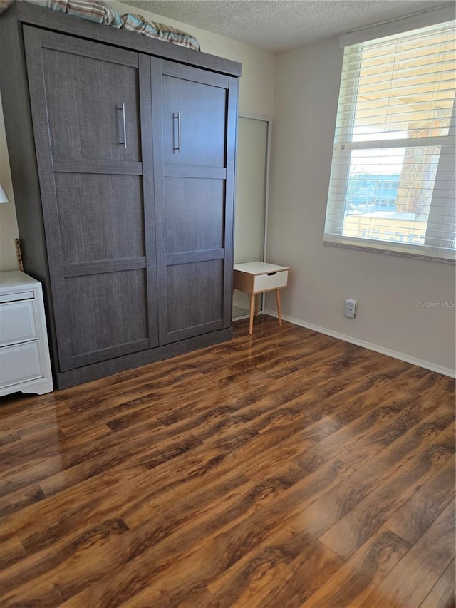 unfurnished bedroom with dark wood-type flooring and a textured ceiling