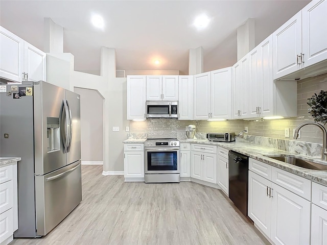 kitchen with appliances with stainless steel finishes, sink, white cabinets, and decorative backsplash