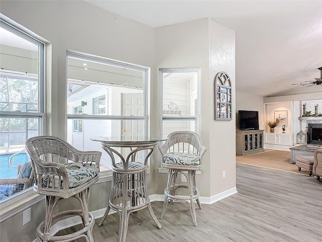 dining space with ceiling fan, lofted ceiling, and light wood-type flooring