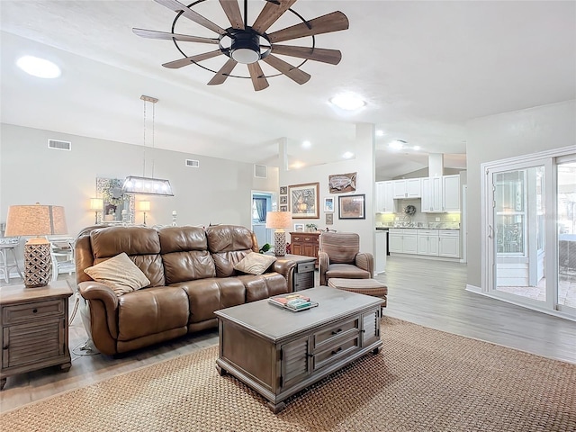 living room featuring ceiling fan, lofted ceiling, and light wood-type flooring