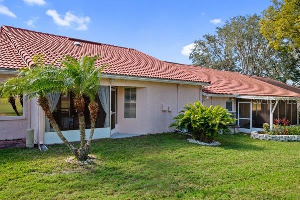 back of property featuring a sunroom and a lawn