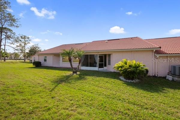 rear view of property with central AC and a lawn