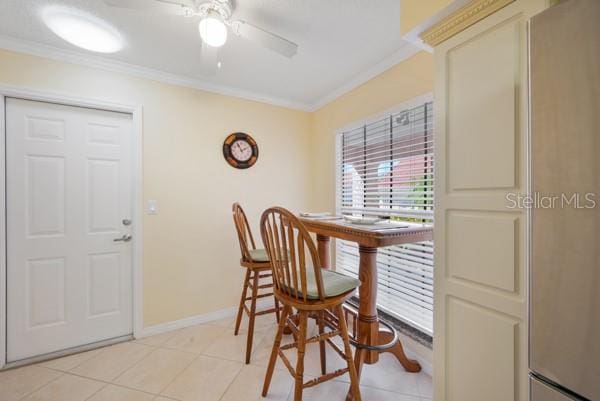 tiled dining room featuring ornamental molding and ceiling fan