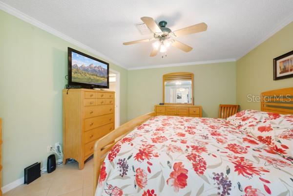 bedroom featuring crown molding, ceiling fan, and light tile patterned flooring