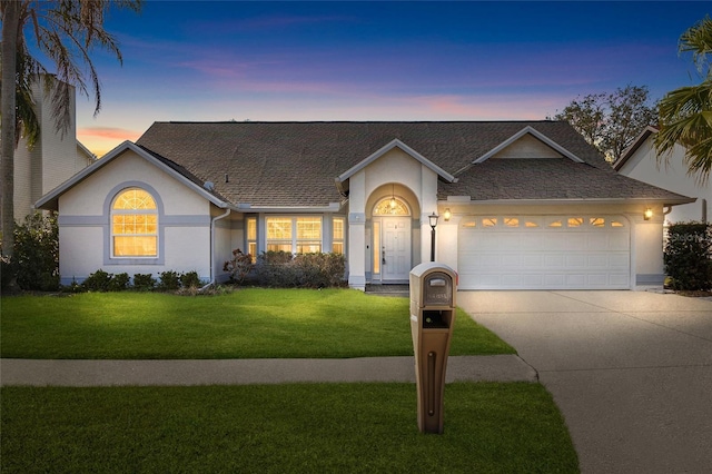 ranch-style house with a garage and a yard