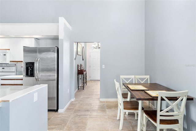 kitchen featuring white cabinetry, white appliances, an inviting chandelier, and decorative backsplash