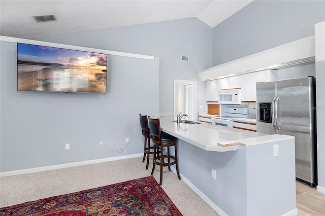 kitchen with lofted ceiling, sink, a kitchen breakfast bar, kitchen peninsula, and white appliances