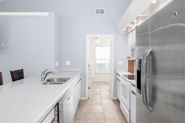 kitchen with white cabinetry, white appliances, light tile patterned flooring, and sink