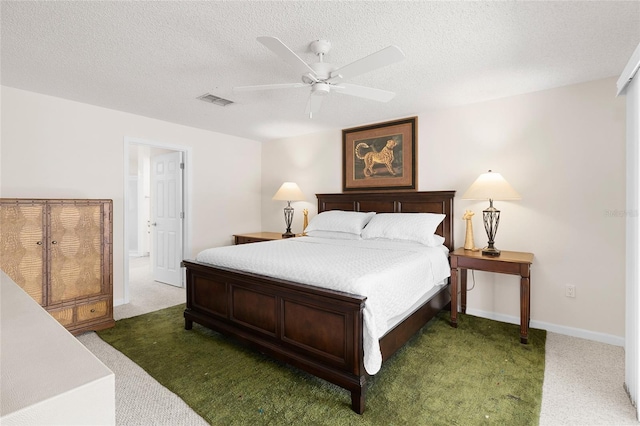 carpeted bedroom with ceiling fan and a textured ceiling