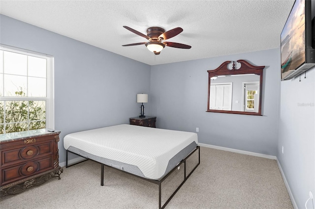 bedroom with ceiling fan, light colored carpet, and a textured ceiling