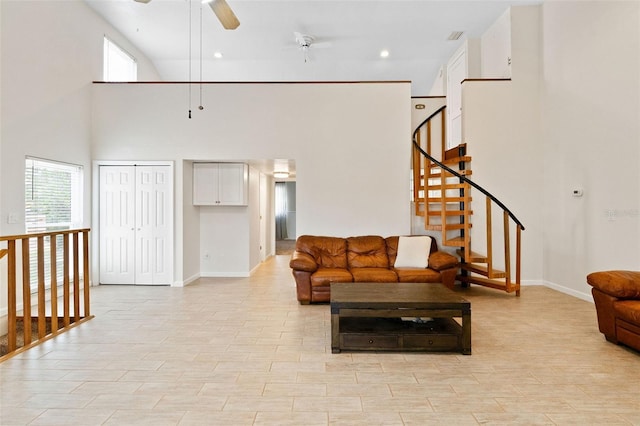 living room featuring ceiling fan, light hardwood / wood-style flooring, and a towering ceiling