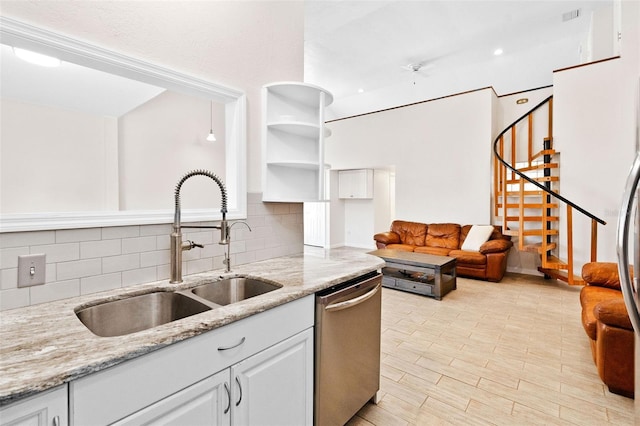 kitchen featuring white cabinetry, sink, light stone countertops, and dishwasher