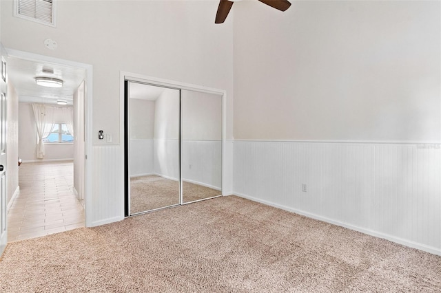 unfurnished bedroom with light colored carpet, ceiling fan, and a closet