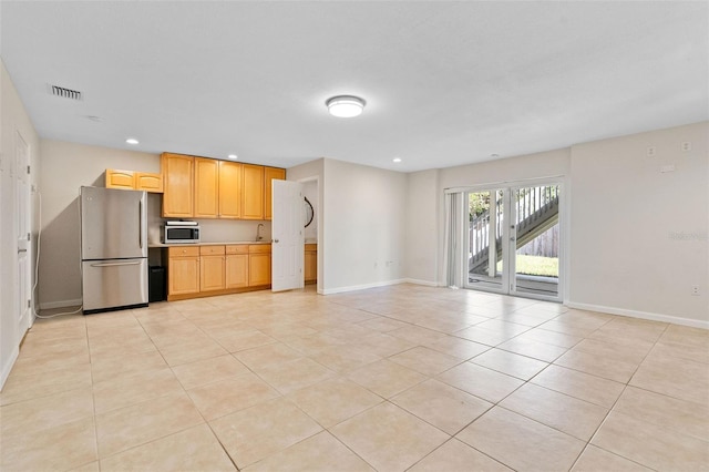 kitchen featuring light tile patterned flooring, appliances with stainless steel finishes, and light brown cabinets