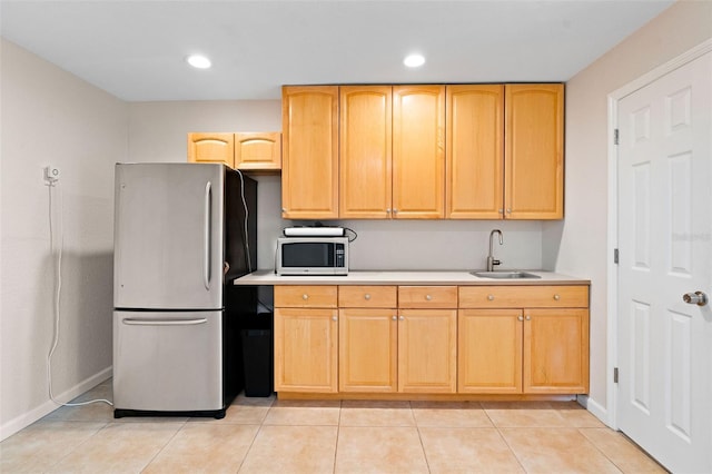 kitchen with light brown cabinetry, sink, stainless steel appliances, and light tile patterned flooring