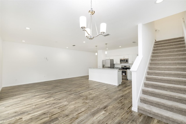 unfurnished living room with an inviting chandelier and light hardwood / wood-style floors