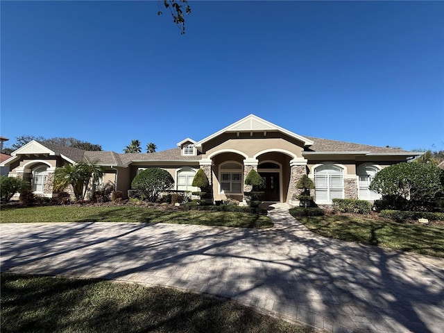 view of front facade featuring stone siding, a front lawn, and stucco siding