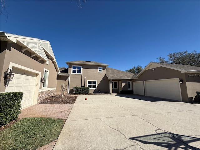 view of front of house featuring a garage, concrete driveway, and stucco siding