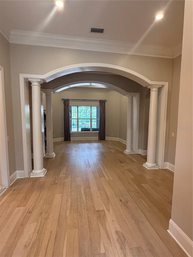 empty room featuring light wood-type flooring, ornate columns, visible vents, and crown molding