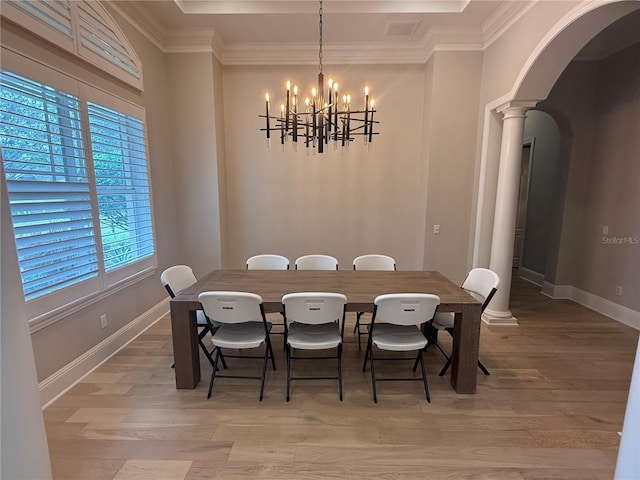 dining space featuring arched walkways, light wood-style flooring, baseboards, ornamental molding, and ornate columns