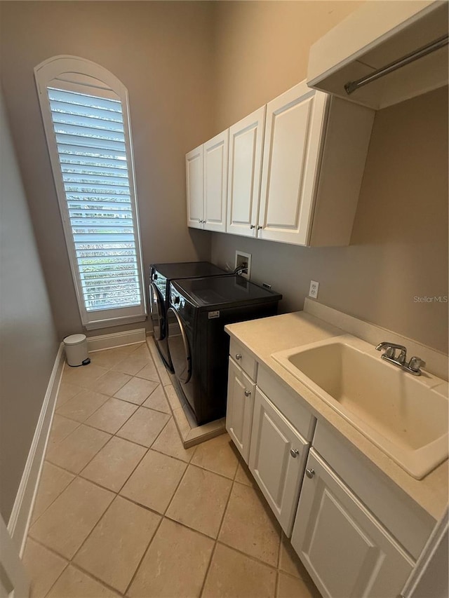 laundry room with cabinet space, baseboards, separate washer and dryer, a sink, and light tile patterned flooring