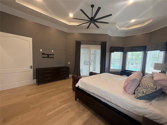 bedroom featuring light wood-type flooring, a tray ceiling, and ornamental molding