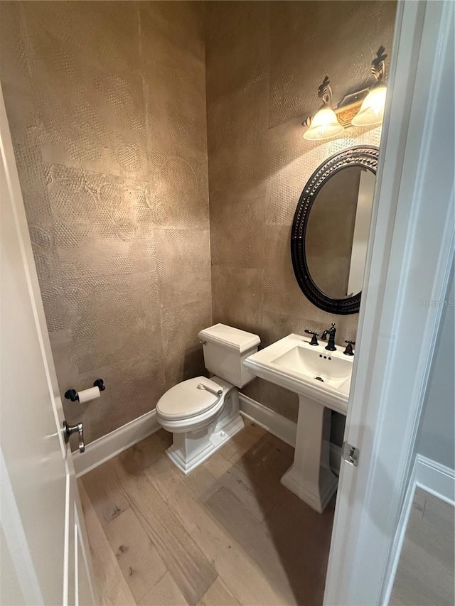 bathroom featuring baseboards, toilet, and wood finished floors