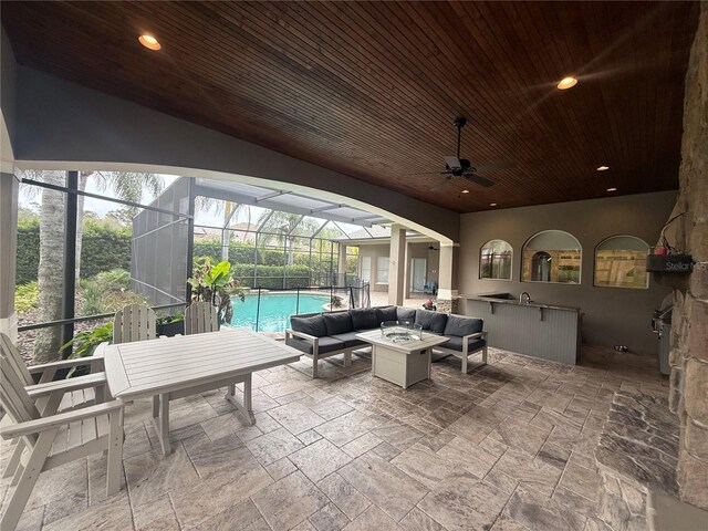 view of patio featuring a ceiling fan, a lanai, an outdoor living space with a fire pit, and an outdoor pool