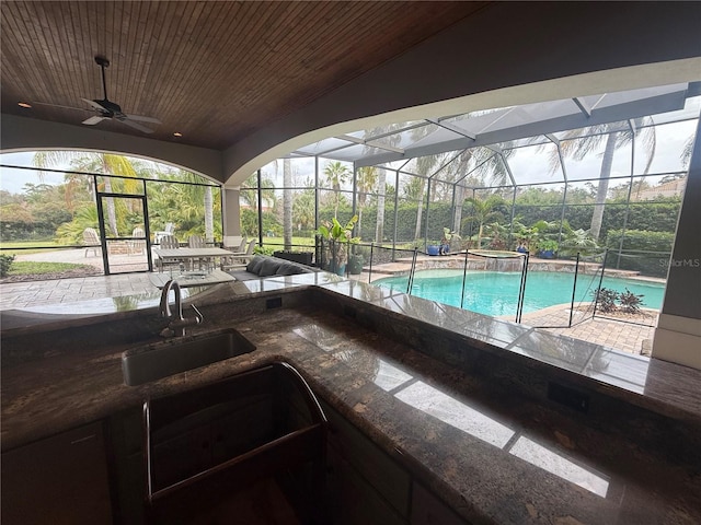 view of swimming pool featuring a patio, a lanai, a pool with connected hot tub, a ceiling fan, and a bar