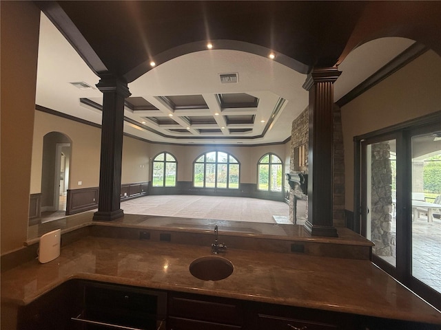 kitchen featuring a wainscoted wall, ornamental molding, coffered ceiling, and ornate columns