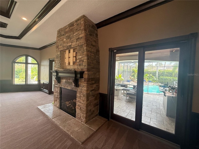 doorway featuring a textured ceiling, a fireplace, crown molding, and carpet flooring