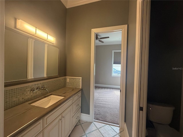 bathroom featuring toilet, decorative backsplash, ornamental molding, vanity, and baseboards