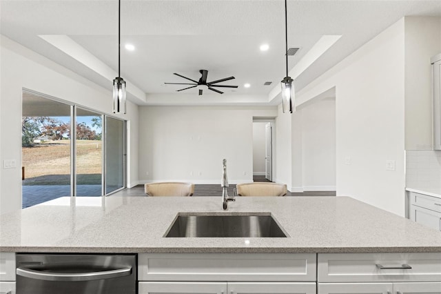 kitchen featuring a raised ceiling, hanging light fixtures, sink, and stainless steel dishwasher