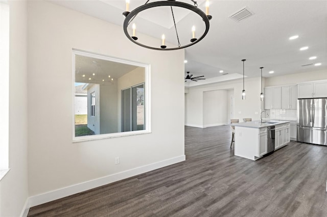 kitchen with appliances with stainless steel finishes, tasteful backsplash, sink, white cabinets, and a kitchen island with sink