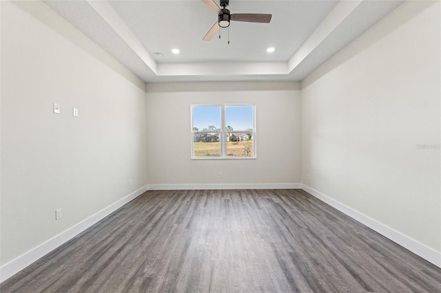 spare room featuring wood-type flooring, a raised ceiling, and ceiling fan