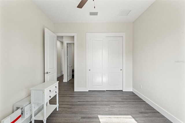 unfurnished bedroom featuring dark wood-type flooring, a closet, and ceiling fan