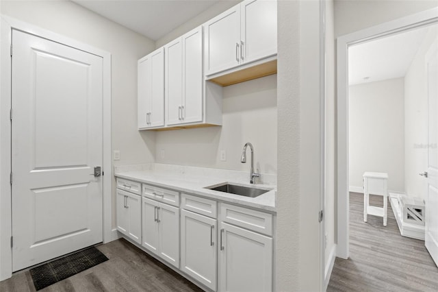 kitchen featuring white cabinetry, sink, wood-type flooring, and light stone countertops