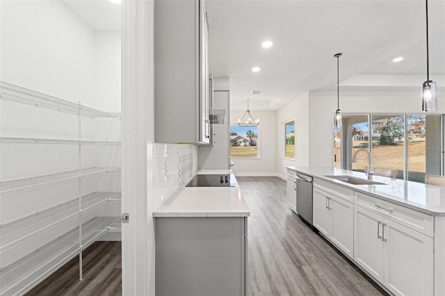 kitchen with sink, light stone counters, white cabinetry, hanging light fixtures, and stainless steel dishwasher