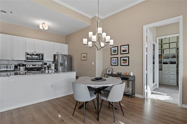 dining area featuring ornamental molding, a chandelier, and hardwood / wood-style floors