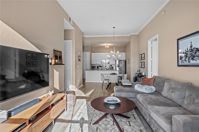 living room with a notable chandelier, light hardwood / wood-style flooring, and ornamental molding