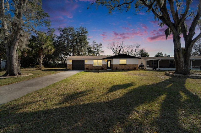 ranch-style house with a garage, a sunroom, and a lawn