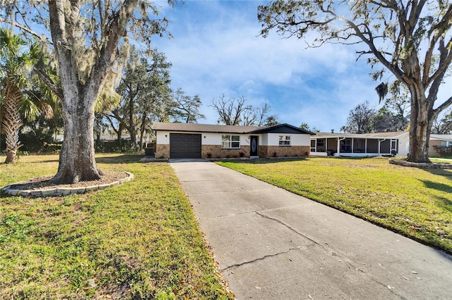 ranch-style home featuring a garage, a sunroom, and a front lawn